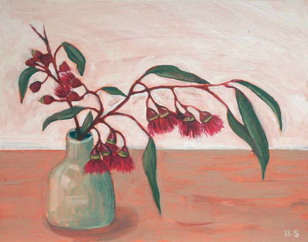 An expressive still life painting of red eucalyptus blossoms arranged in a pale green ceramic vase. Long, curved branches with dark green leaves and clusters of hanging red flowers stretch across a soft pink background, above a warm terracotta tabletop.